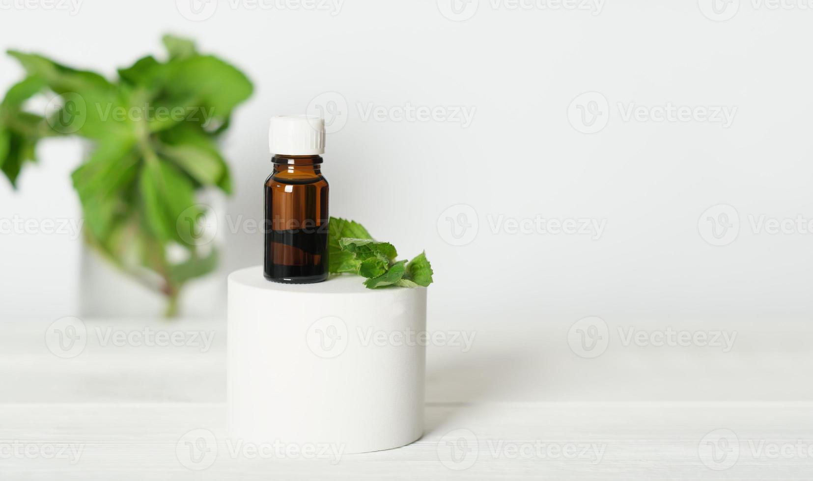 óleo de aromaterapia em uma garrafa de vidro browm no pódio com folhas de hortelã. menta e mentol como fragrâncias calmantes e relaxantes, óleo essencial para o ambiente. foto