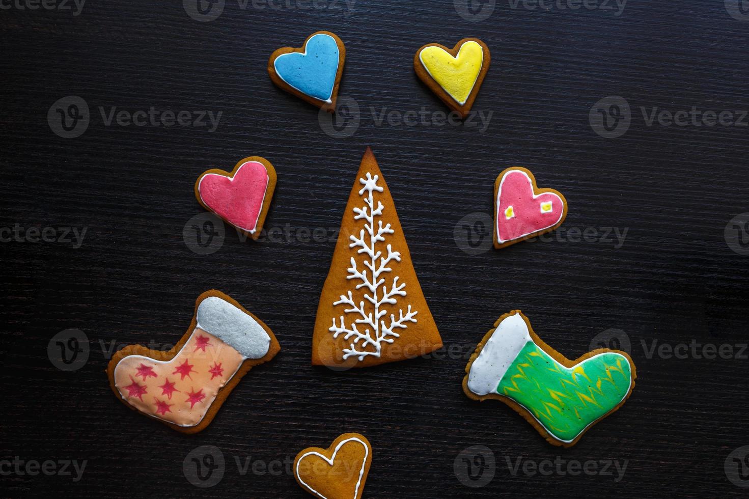 biscoitos de gengibre festivos artesanais em forma de estrelas, flocos de neve, pessoas, meias, funcionários, luvas, árvores de natal, corações para férias de natal e ano novo em fundo preto de madeira foto