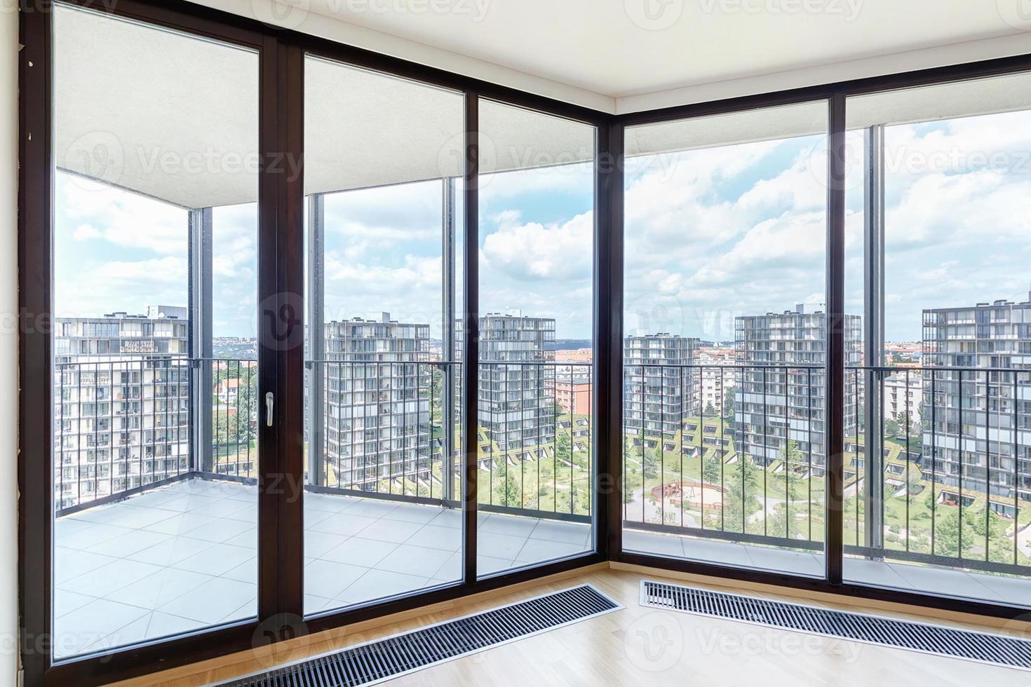 interior de apartamento loft vazio branco moderno com piso em parquet e janelas panorâmicas, com vista para a cidade metrópole foto