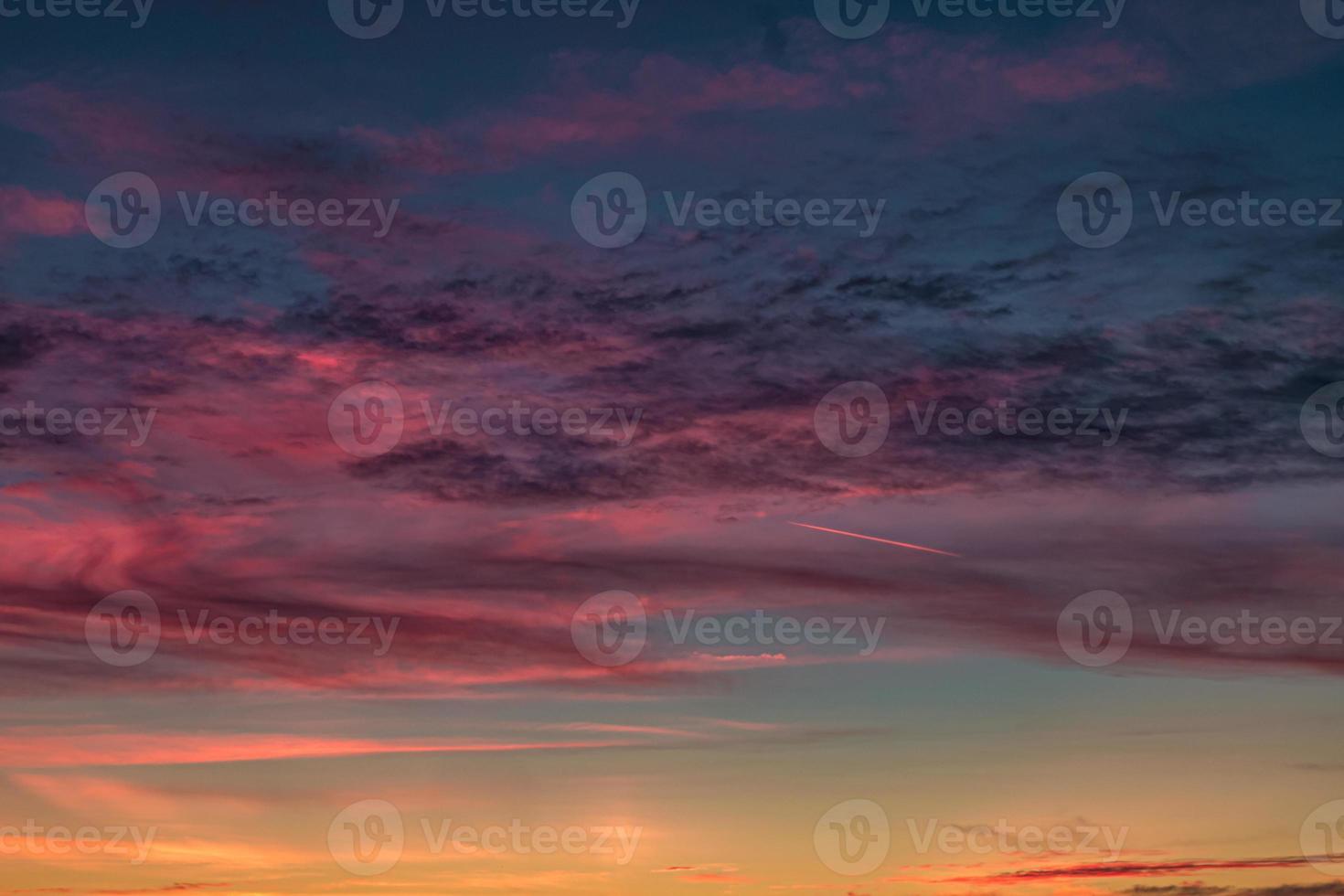 fundo de céu azul violeta vermelho pôr do sol com nuvens de cirrostratus rolando encaracolados fofos à noite. bom tempo ventoso foto