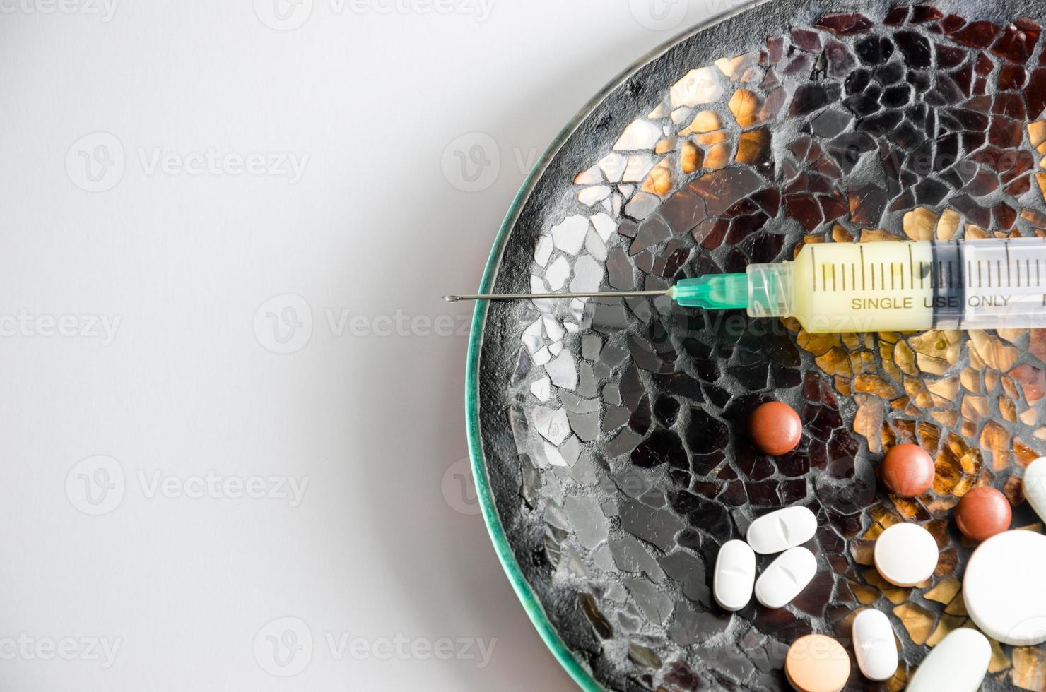 seringa e comprimidos em um prato foto