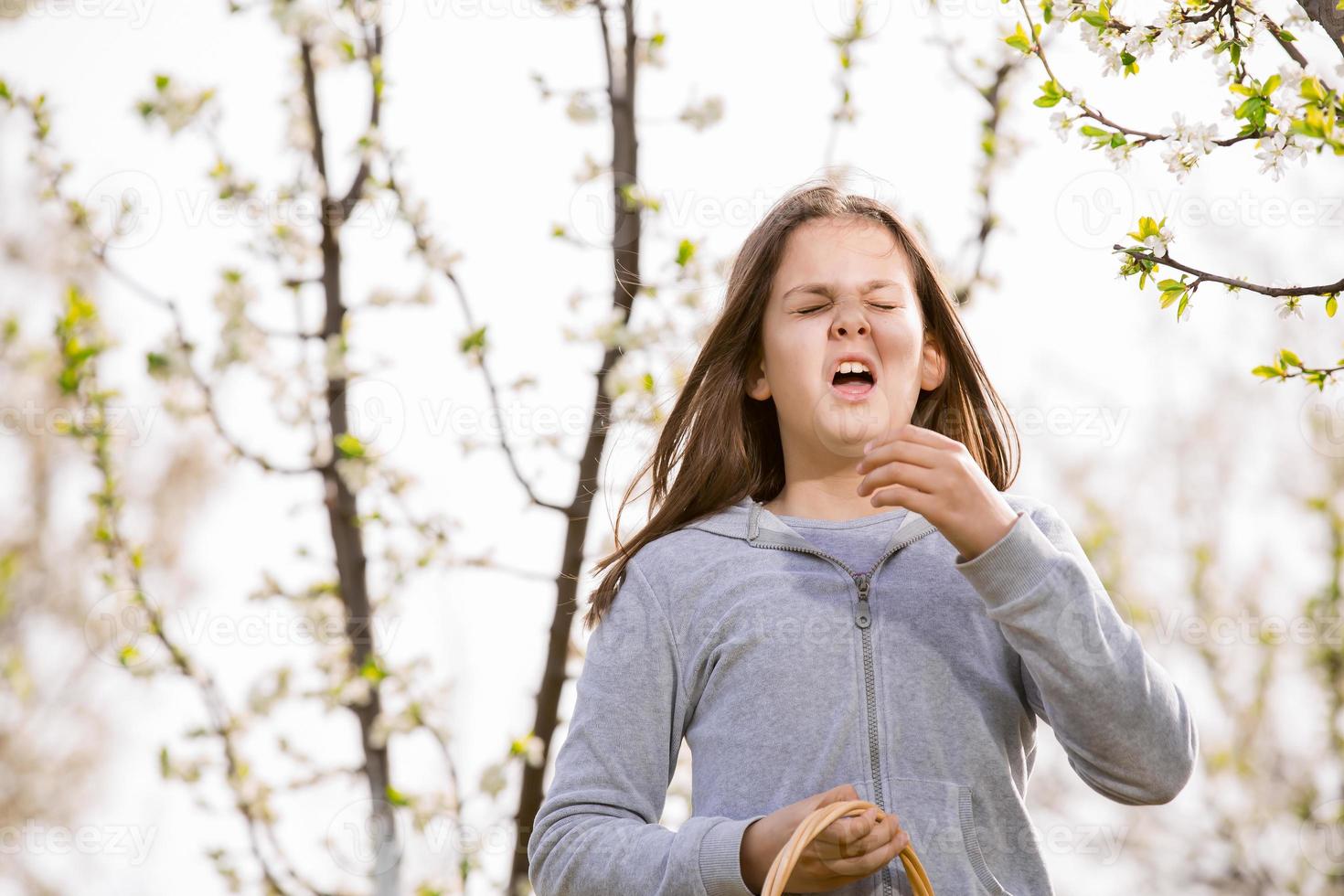 garota com alergia ao ar livre. a menina espirra foto