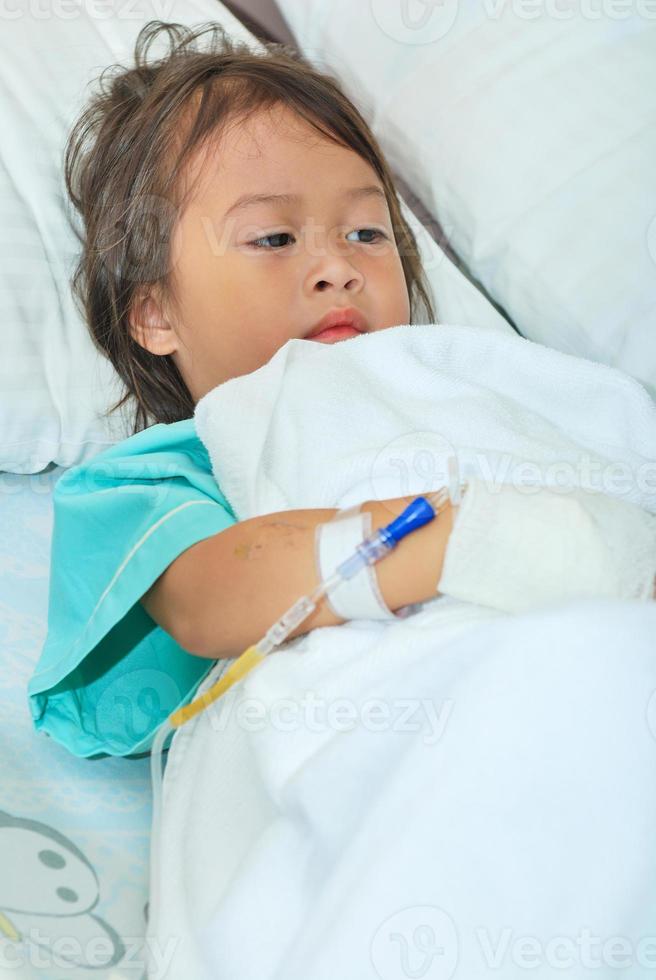 menina doente na cama do hospital foto