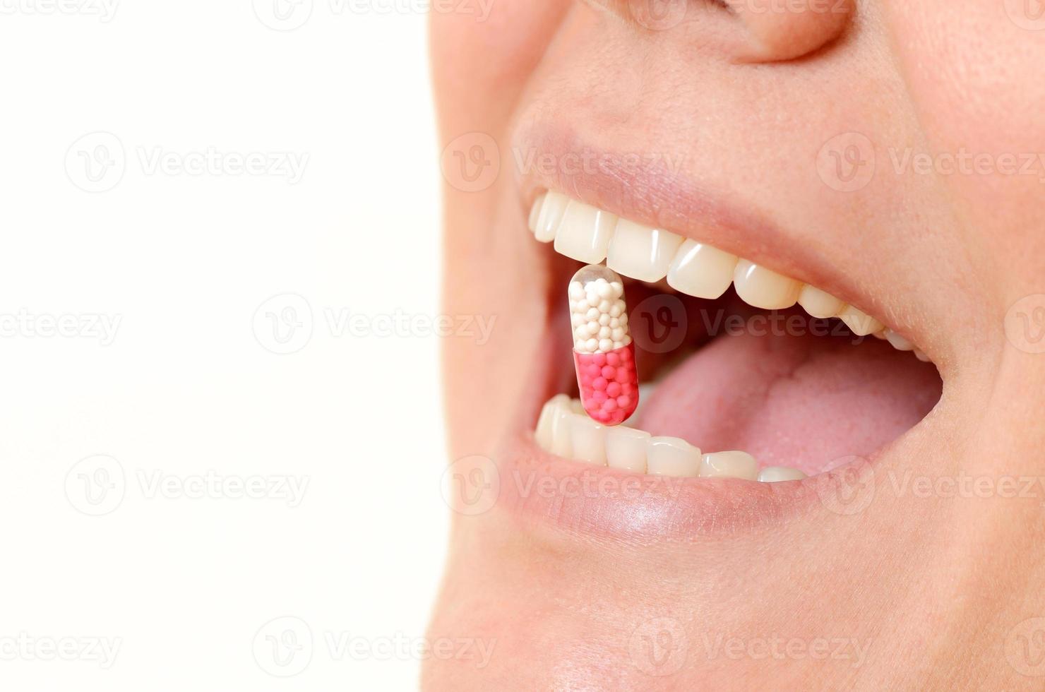 close-up de comprimido na boca da mulher foto