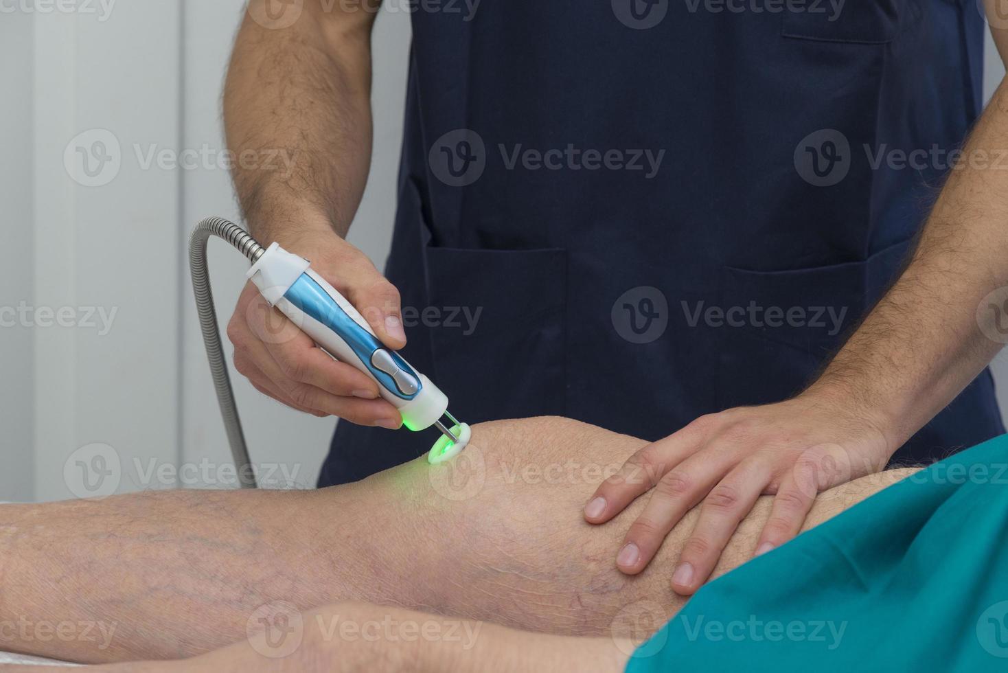 fisioterapeuta auxiliando o joelho de um paciente na reabilitação foto