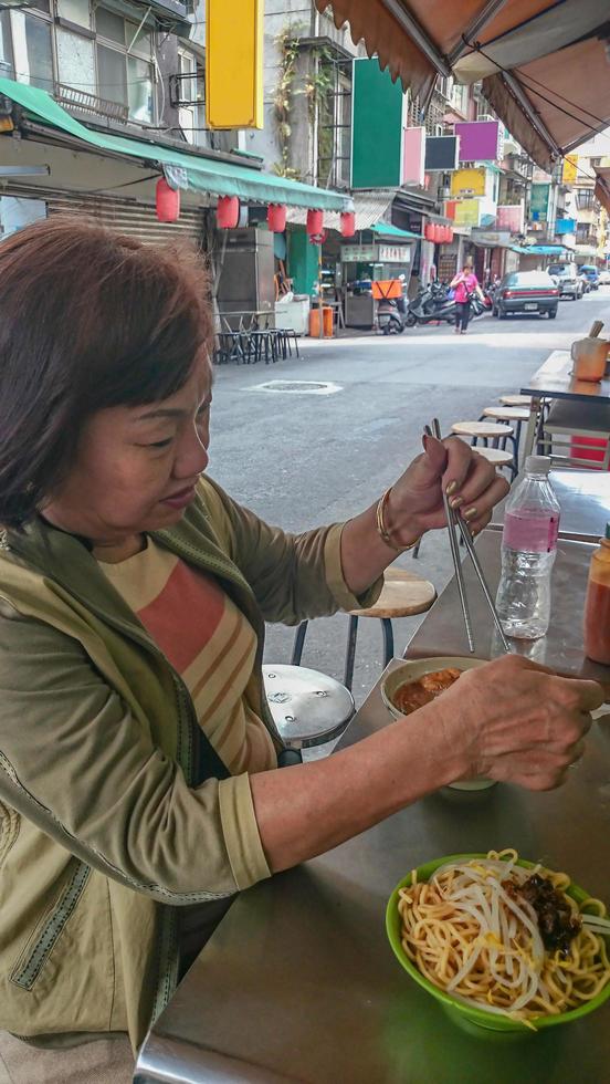 mulheres asiáticas idosas comem comida de rua de macarrão de taiwan na cidade de taipei taiwan foto