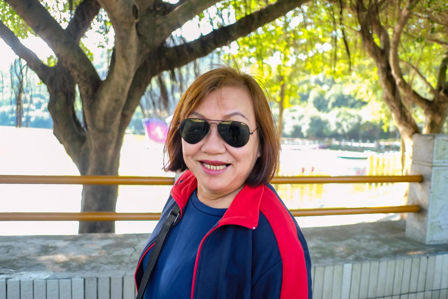 foto de retrato de mulheres asiáticas sênior usam óculos de sol sorriso muito feliz enquanto caminhava ao lado do lago no parque de montanha xiqiao. foshan city china