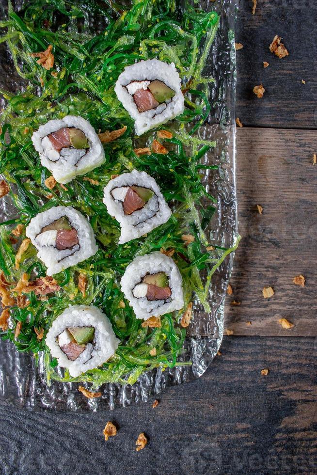 sushi com atum e camarão na cama de salada de algas verdes cama plana foto