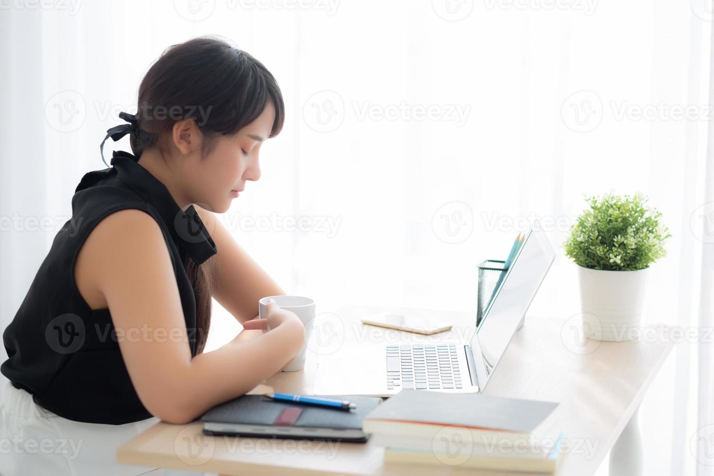 bela jovem mulher asiática freelance sorrindo trabalhando e no computador portátil no escritório de mesa com profissional, garota usando notebook e bebida café, negócios e conceito de estilo de vida. foto