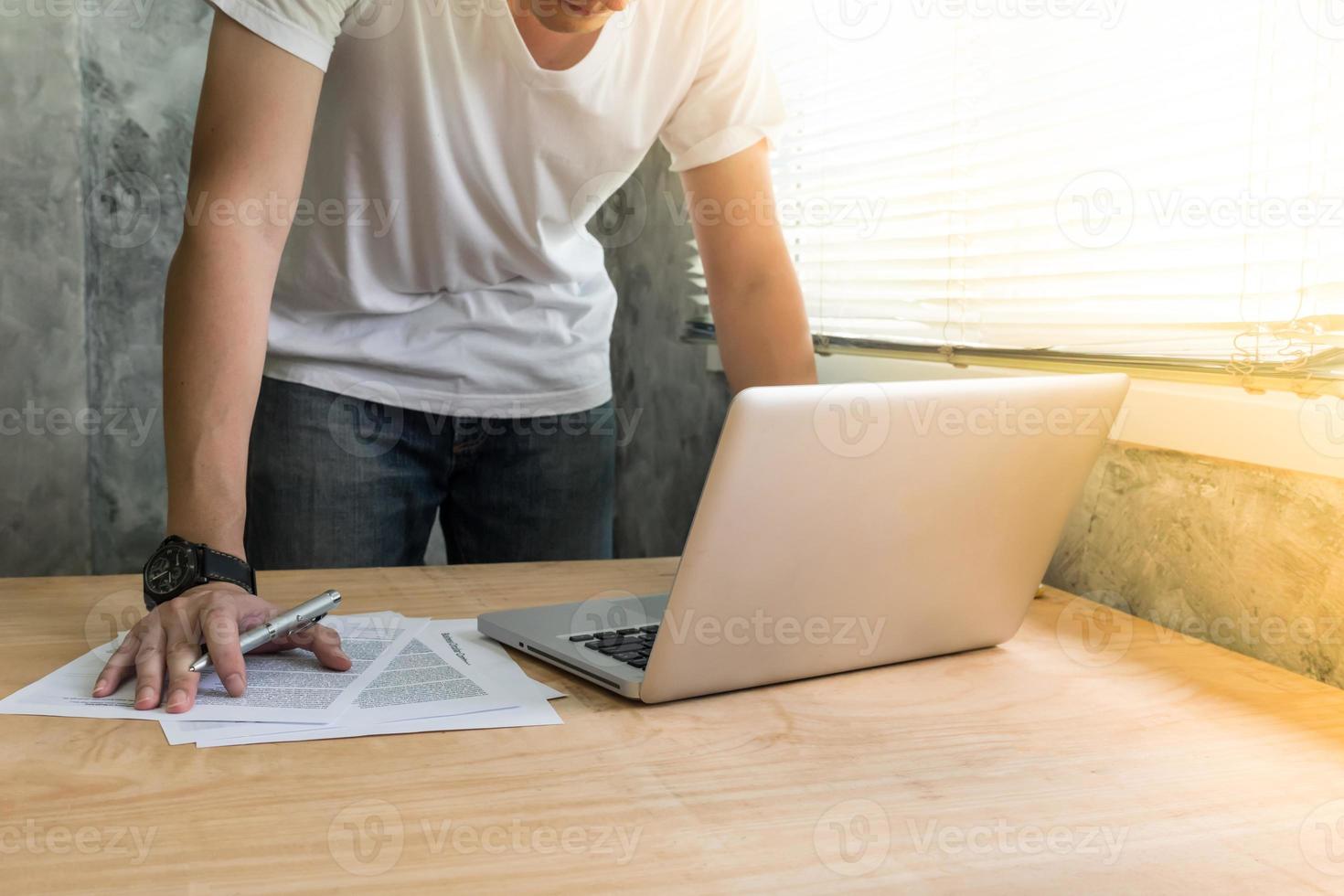 um homem que trabalha no escritório. documento de análise e usando laptop foto