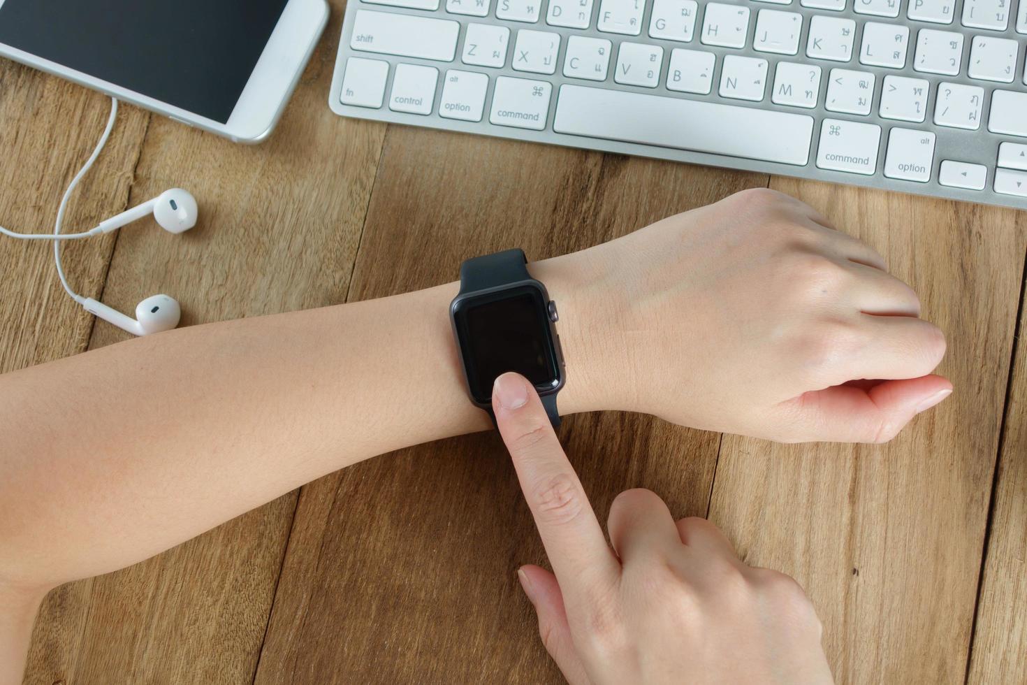 mulher usando relógio inteligente touchscreen na mesa de trabalho foto