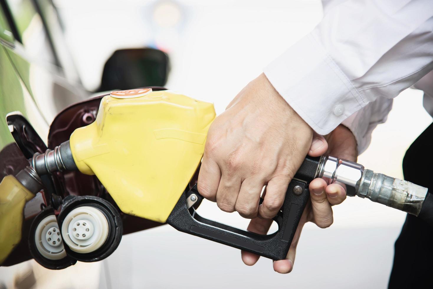 homem colocando gasolina em seu carro em um posto de gasolina da bomba foto
