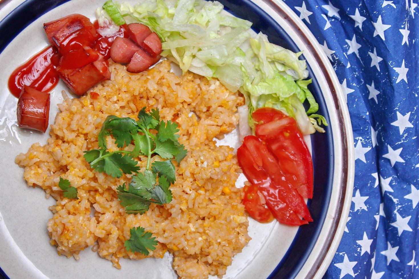 arroz frito com linguiça frita servido em um prato cremoso com tomate e pepino. foto