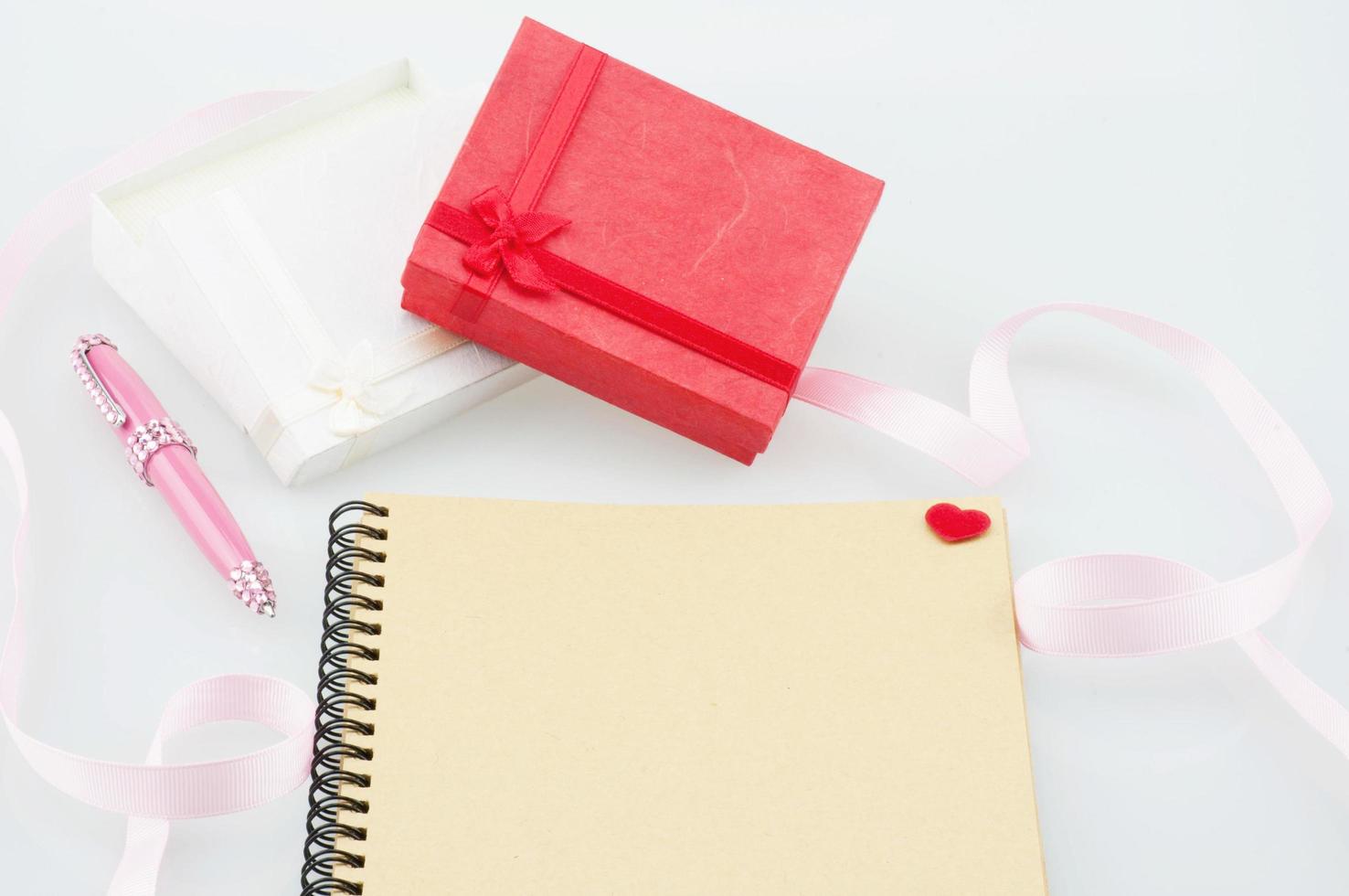 caderno com caneta rosa e caixas de presente com decoração de fita - ecard amor com conceito de presentes foto
