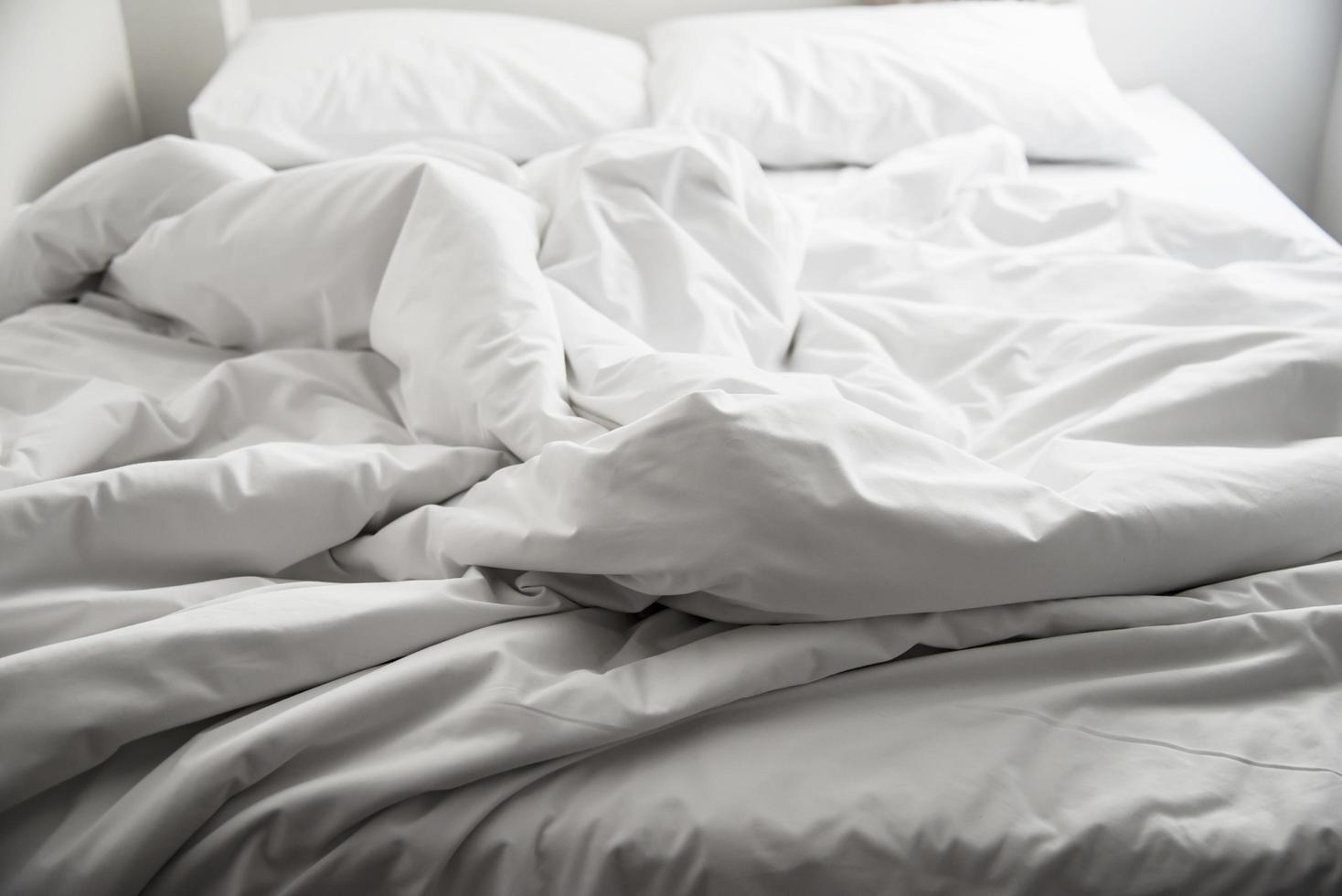 lençol de cama de casal branco usado em um hotel - hotel para conceito de viagem de casal foto