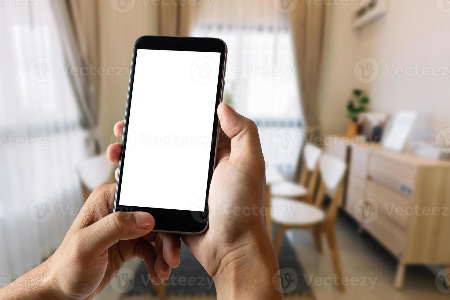 uma mão de homem segurando o dispositivo de telefone inteligente na sala de escritório brilhante foto