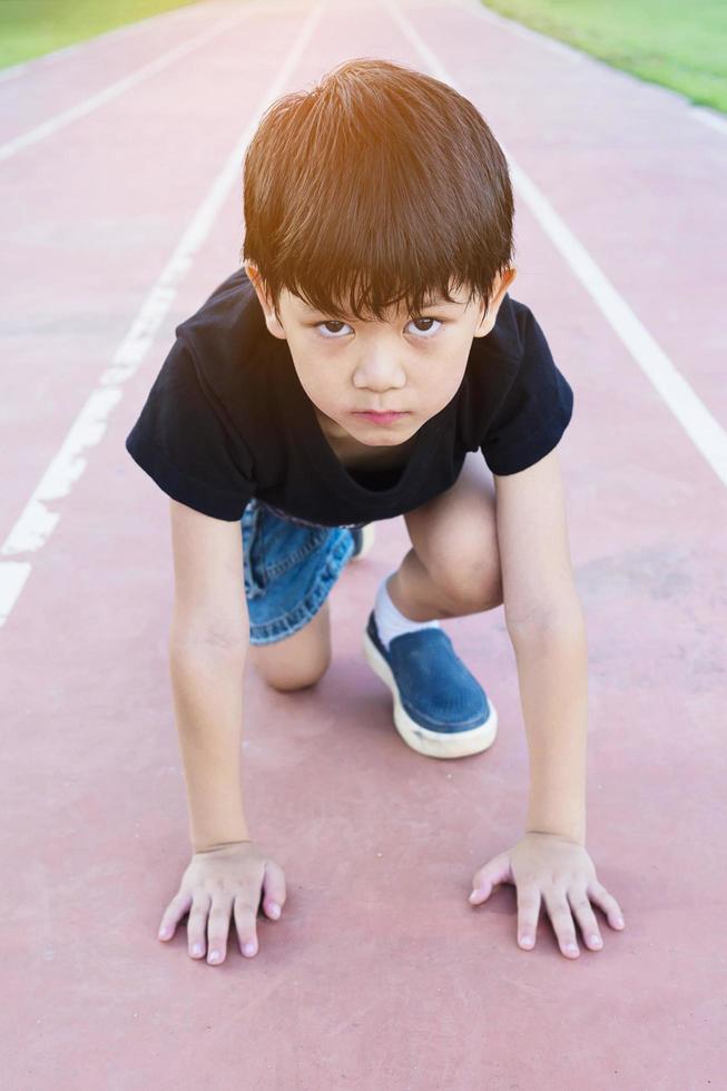 menino de escola saudável pronto para correr no ponto de partida, conceito de competição ativa foto
