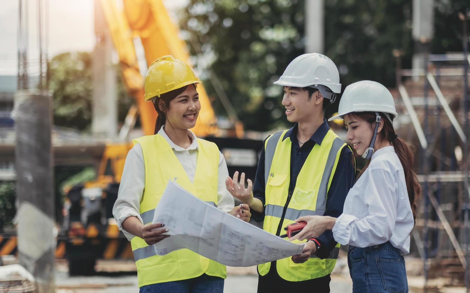 três especialistas inspecionam canteiros de obras de edifícios comerciais e canteiros de obras segurando plantas foto