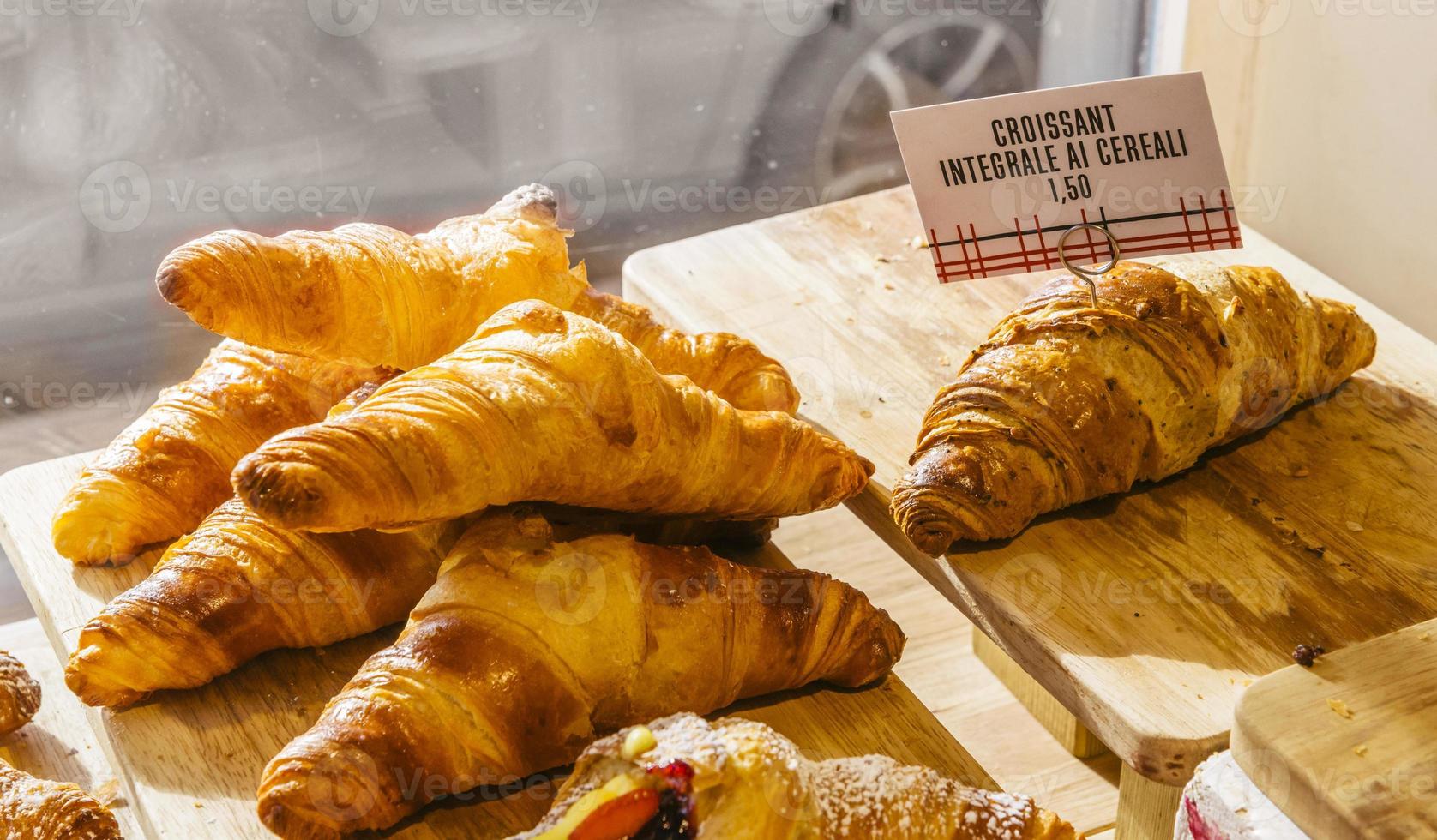 vários sabores de croissant ou como na itália seu chamado brioche em exposição em uma padaria em milão, itália com preço e sinal - albicocca significa geléia em italiano foto