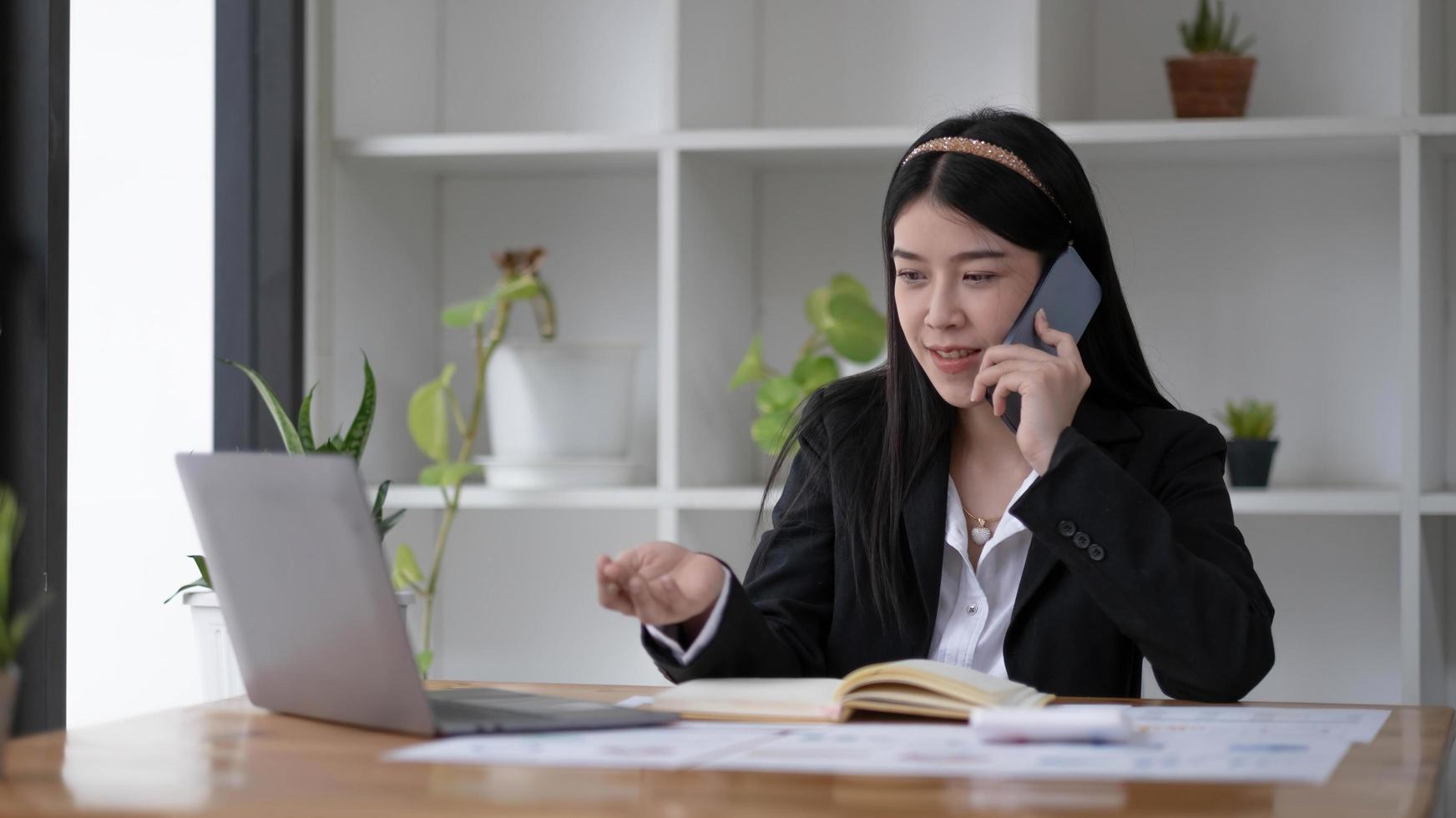 empresária asiática falando ao telefone com o cliente no escritório. foto