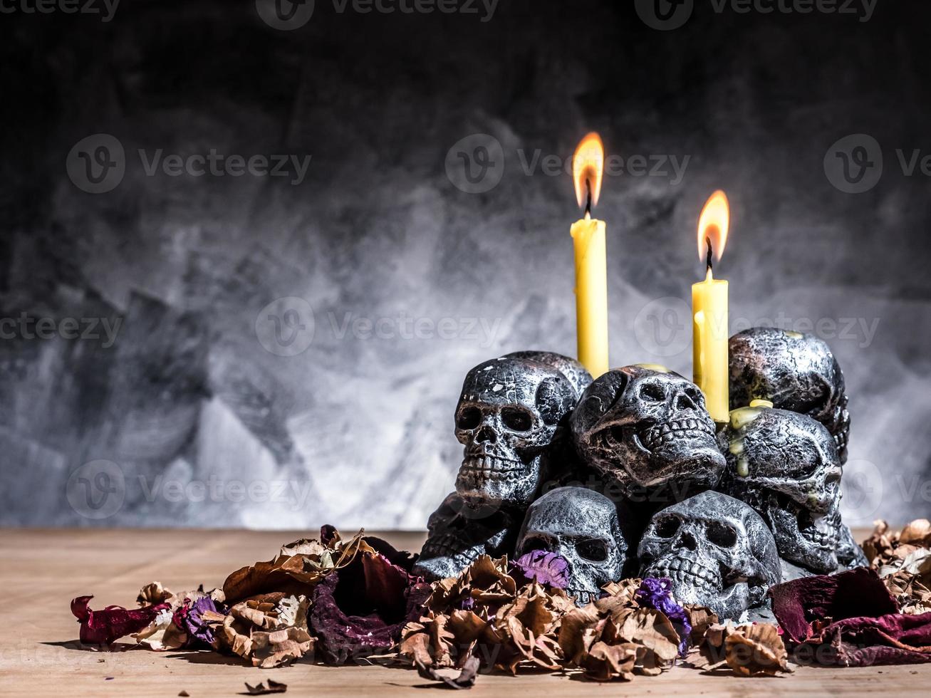 caveiras com vela acesa e flores secas em fundo escuro. foto