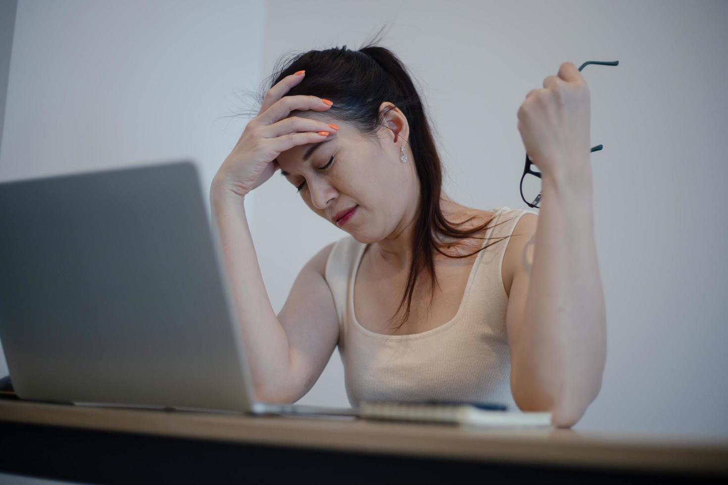 mulher sentindo dor depois de trabalhar no computador portátil por um longo tempo, conceito de síndrome de escritório foto
