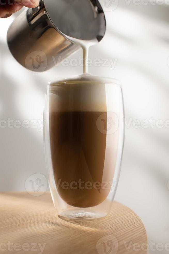 cappuccino em um copo de vidro em uma mesa de madeira, café e espuma de leite. foto