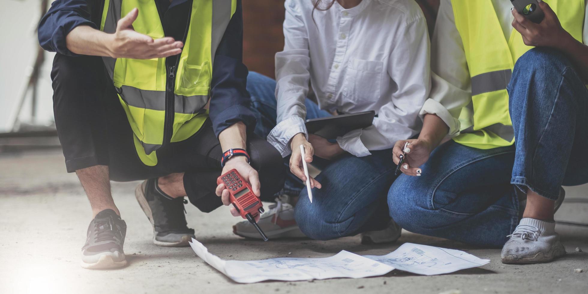 construção profissional e equipe de engenheiros trabalhando no local de trabalho. arquiteto negro profissional e trabalhador da construção civil trabalhando olham para o plano de planta no local. foto