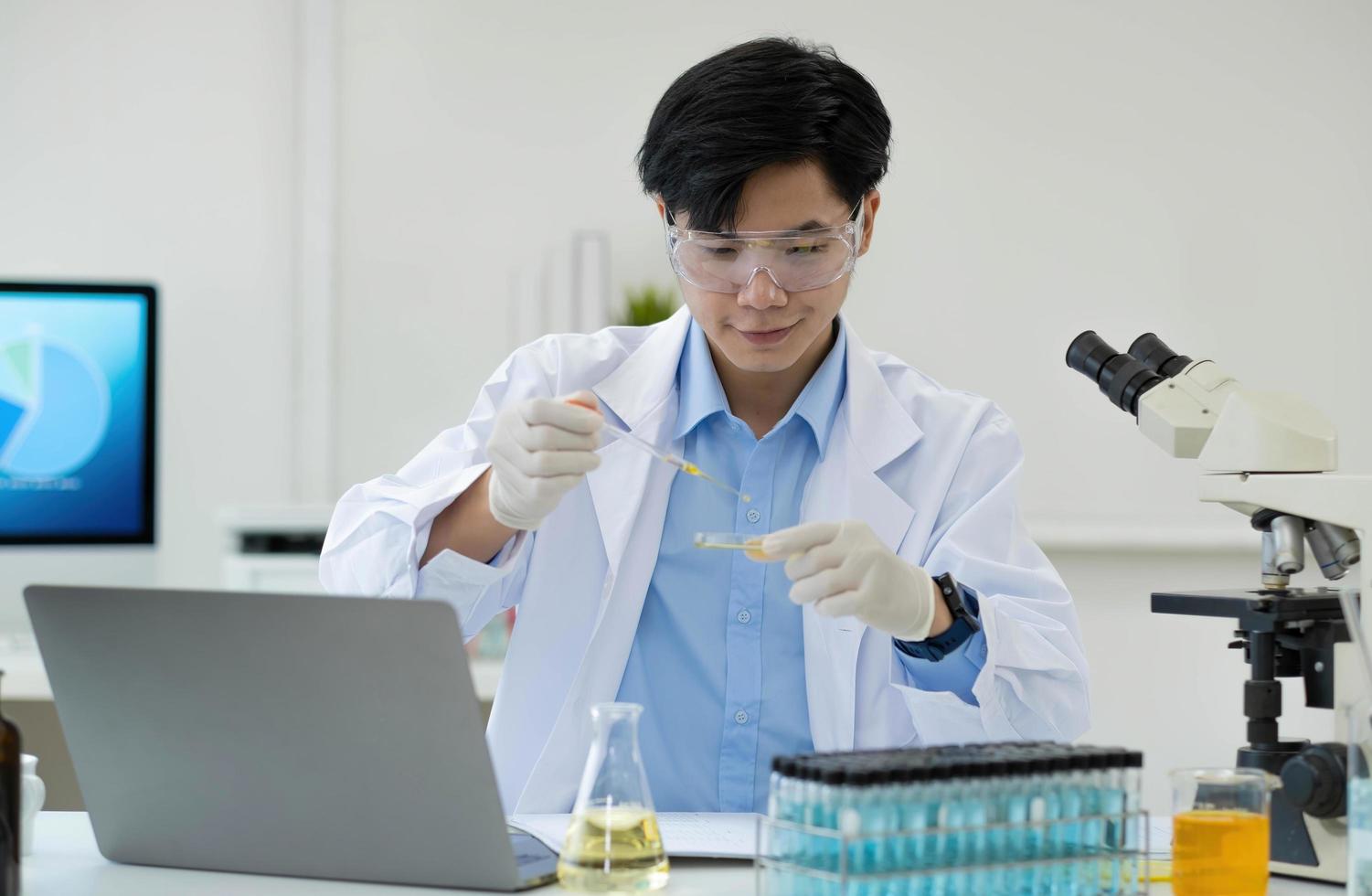 retrato de laboratório de pesquisa médica de um cientista masculino bonito usando computador tablet digital, analisando bioquímicos líquidos em um frasco de laboratório. foto