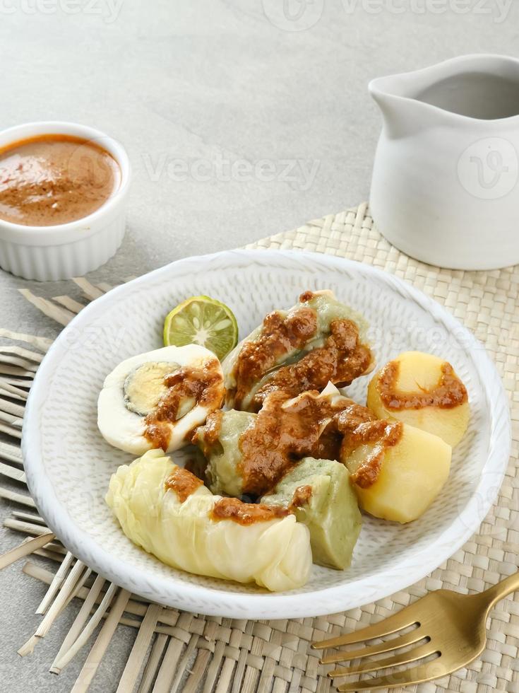 siomay bandung, bolinhos cozidos no vapor com ovo cozido, tofu, batatas e rolo de repolho. comida de rua tradicional indonésia com molho de amendoim e molho de soja, servido com limão verde. foto