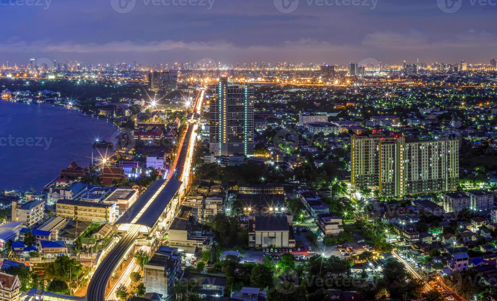 luzes de rua e luzes de casas residenciais nos subúrbios durante o pôr do sol, tráfego de veículos de tráfego de barcos em samut prakan, tailândia foto