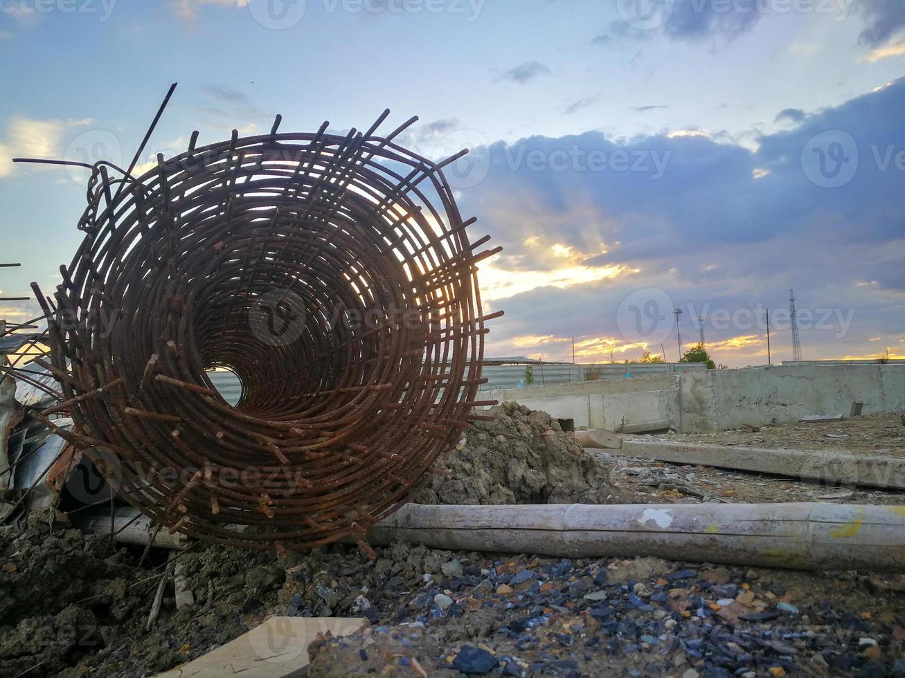 rolos de aço enferrujados em projetos de construção. aço e bambu em pilhas de barro e pedra foto