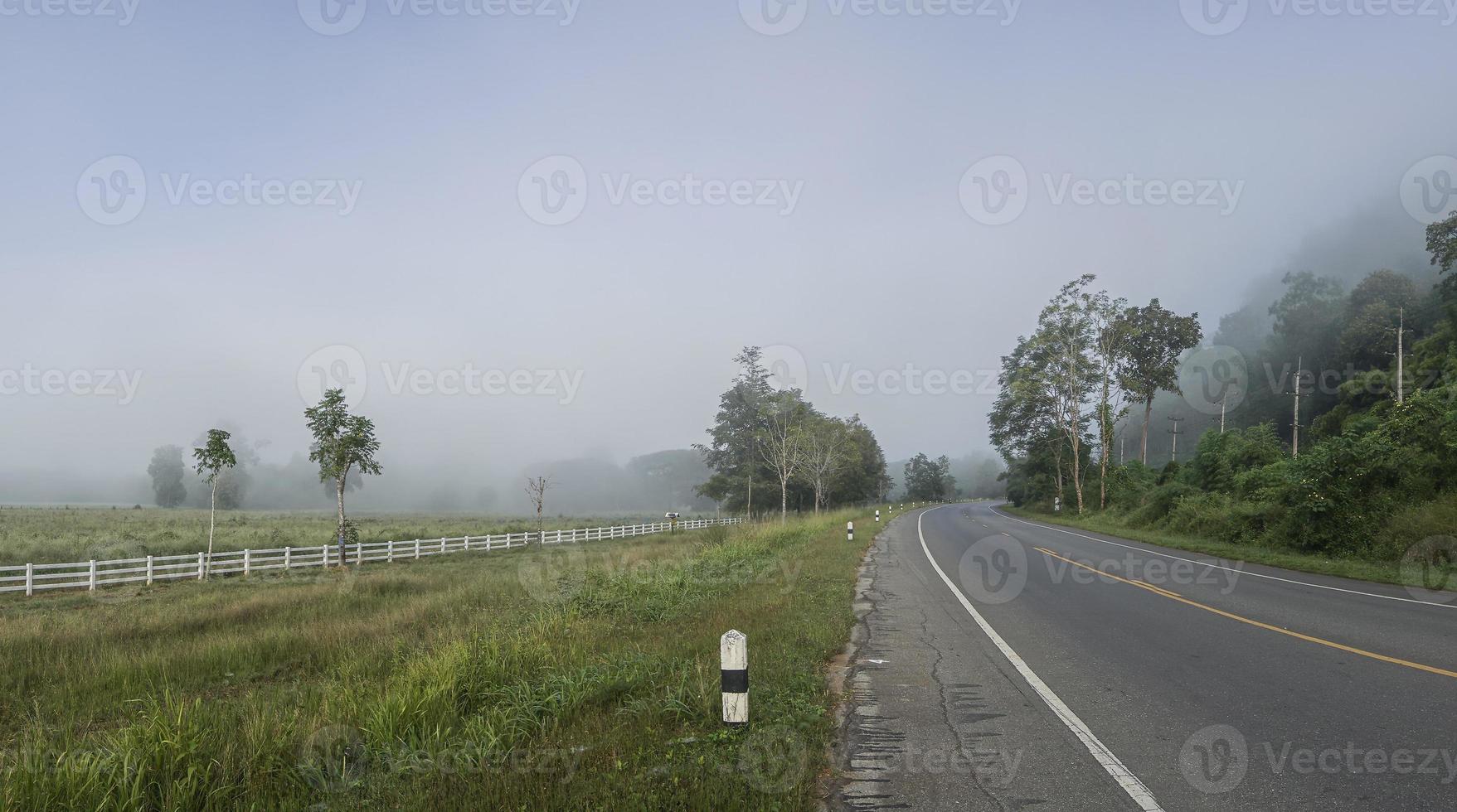 a estrada entre as montanhas e os arrozais cobertos de neblina. a estrada para a vila de pilok, província de kanchanaburi, tailândia. foto