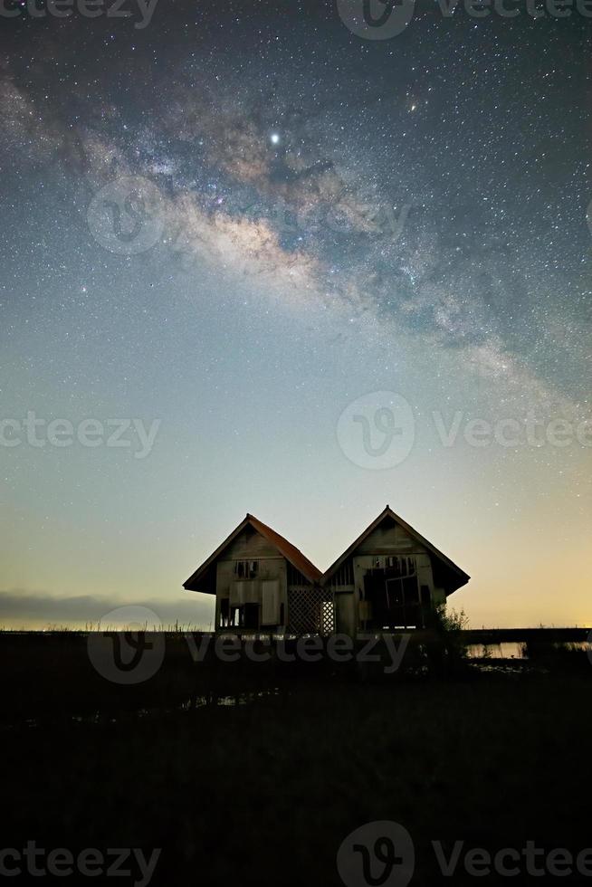 via láctea, velha casa abandonada, telhado vermelho em campo aberto foto