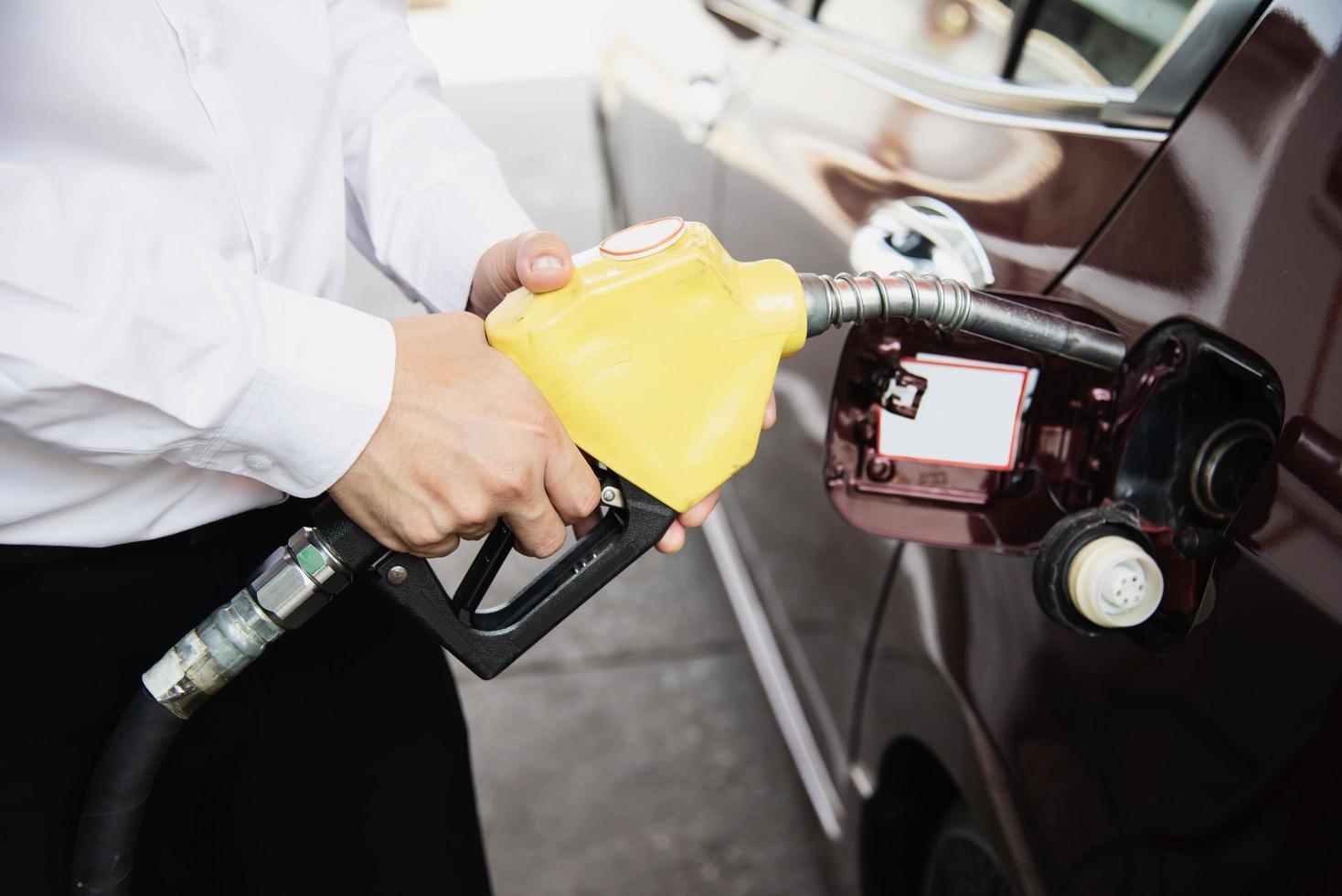 homem colocando gasolina em seu carro em um posto de gasolina da bomba foto
