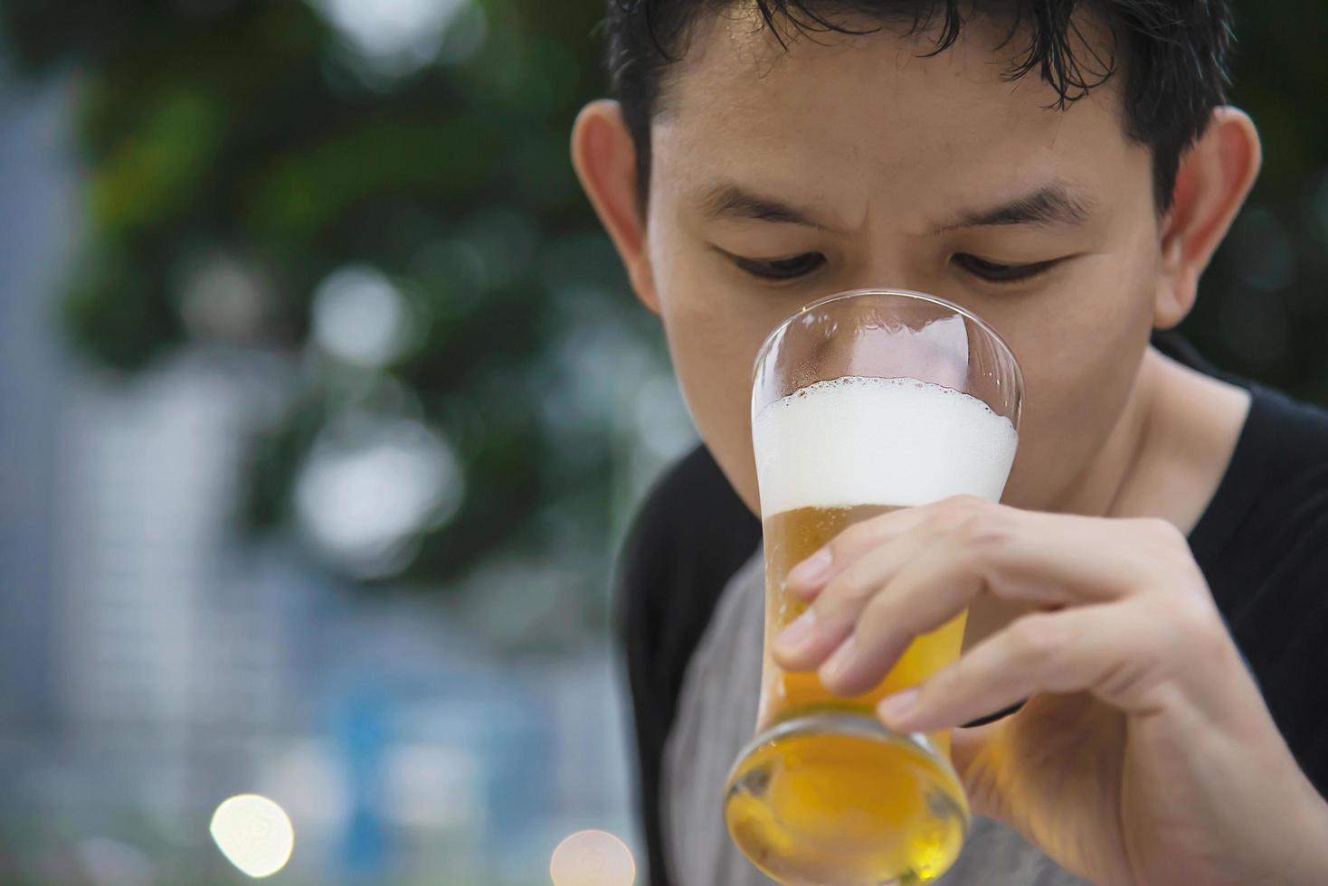 homem asiático bebendo cerveja no restaurante do jardim verde - as pessoas relaxam desfrutam do conceito de estilo de vida de refrigerantes foto