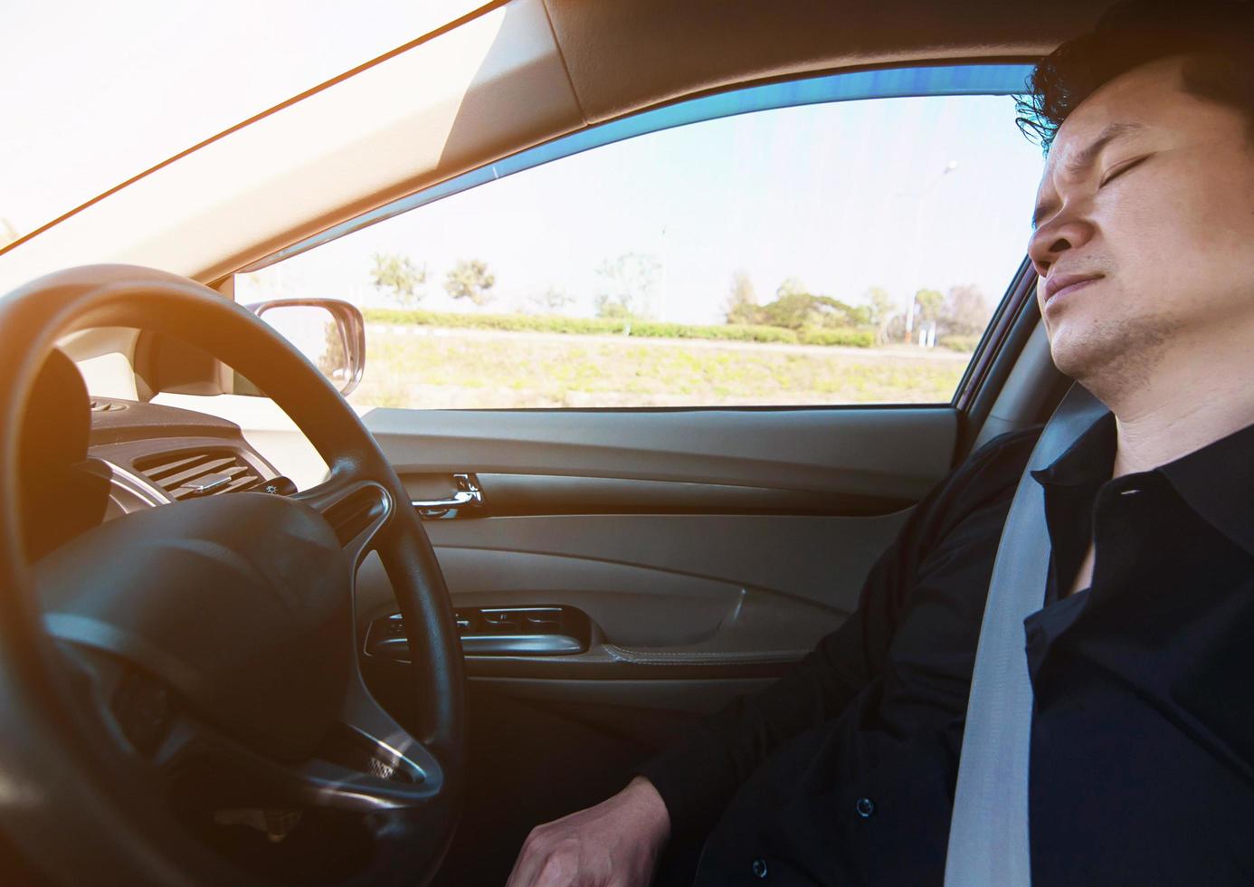 homem dorme no carro enquanto dirige na estrada - pessoas tentaram de longa viagem e conceito de tráfego foto