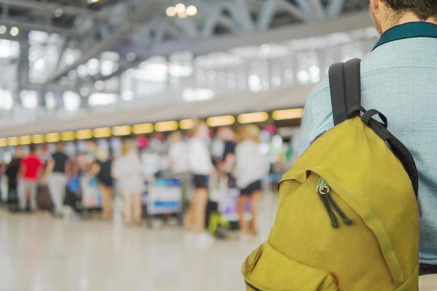 imagem focada suave do viajante sobre a longa fila de passageiros borrada esperando o check-in nos balcões de check-in do aeroporto foto