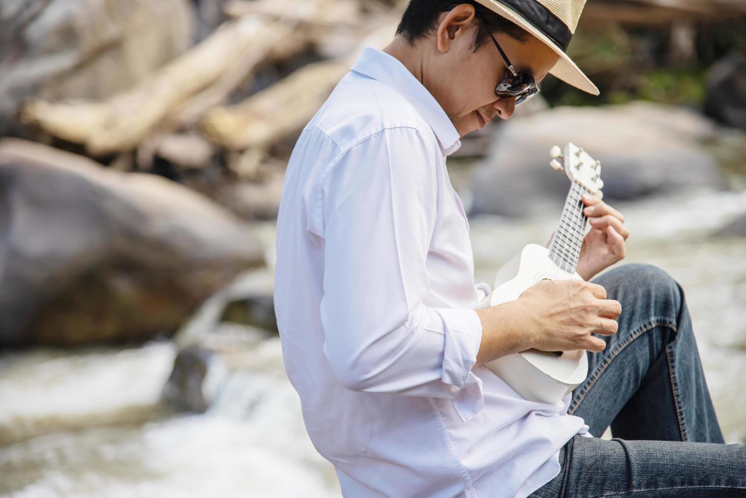 homem toca ukulele novo no estilo de vida de pessoas do rio e instrumentos musicais no conceito de natureza foto
