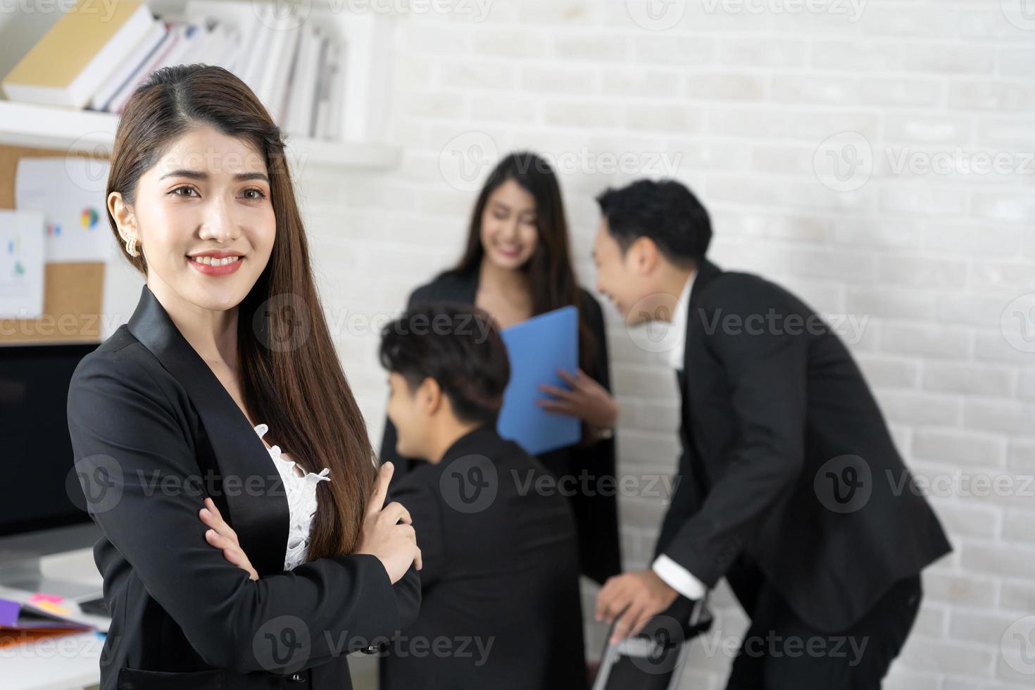 empresária sorrindo feliz em pé com gesto de braços cruzados no escritório durante reunião de negócios. foto