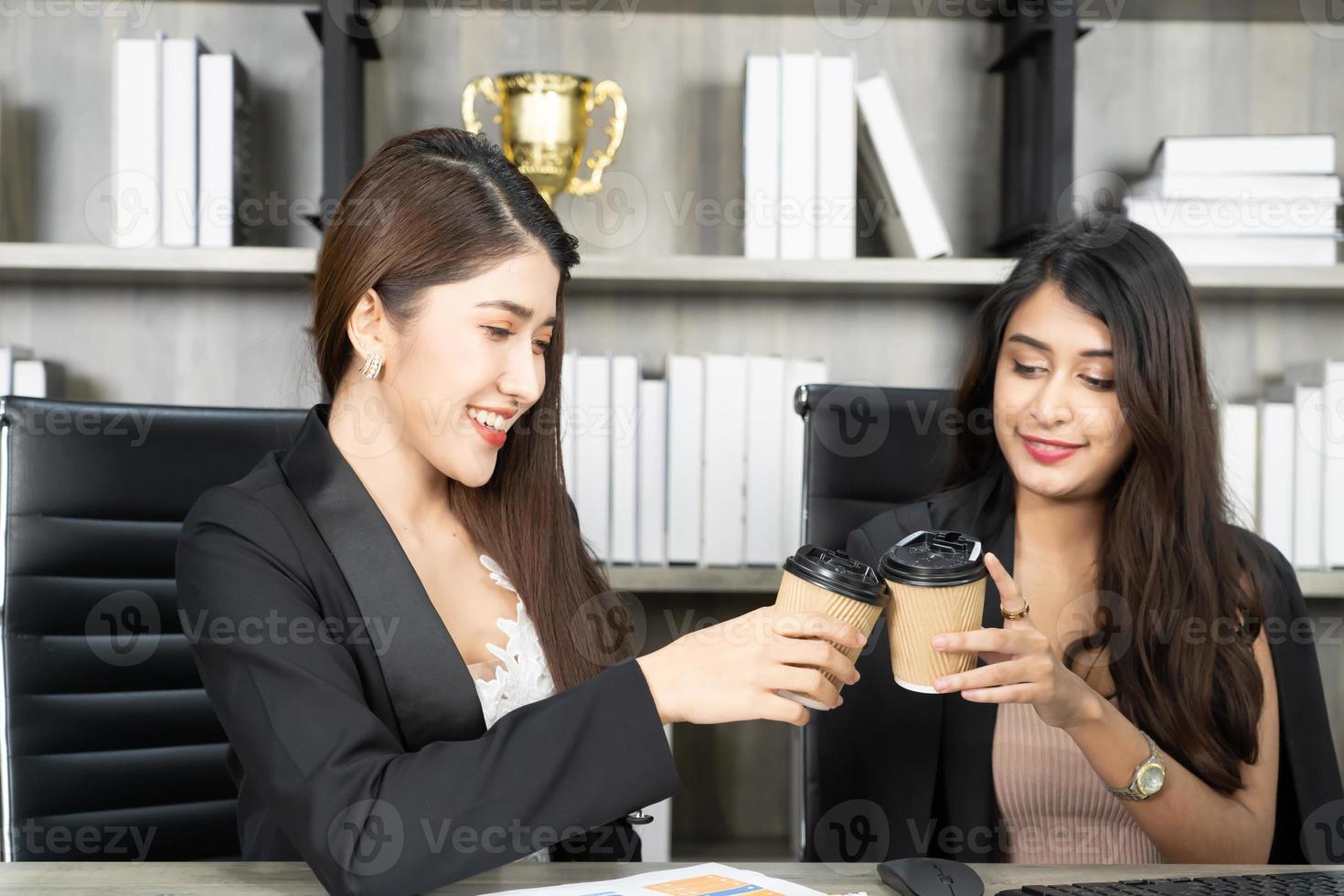 pausa para o café do escritório com duas colegas sentadas conversando sobre xícaras de café. mulher de negócios asiáticos segurando a xícara de café no escritório. foto