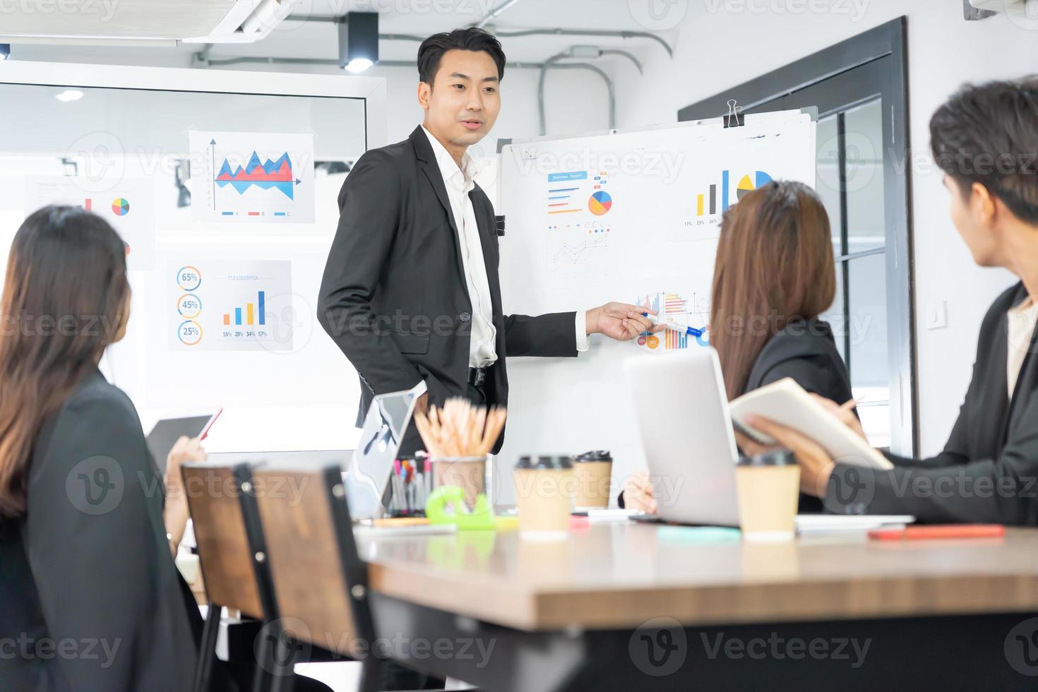 foco seletivo. apresentação de negócios. gerente de projeto apontando para a área de trabalho apresentando dados estatísticos, informando diversos grupos de funcionários. demonstra estatísticas. foto