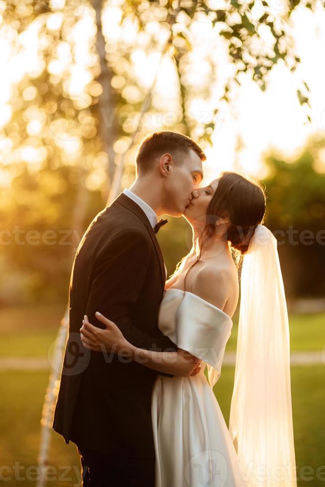 jovem casal o noivo em um terno preto e a noiva em um vestido curto branco foto