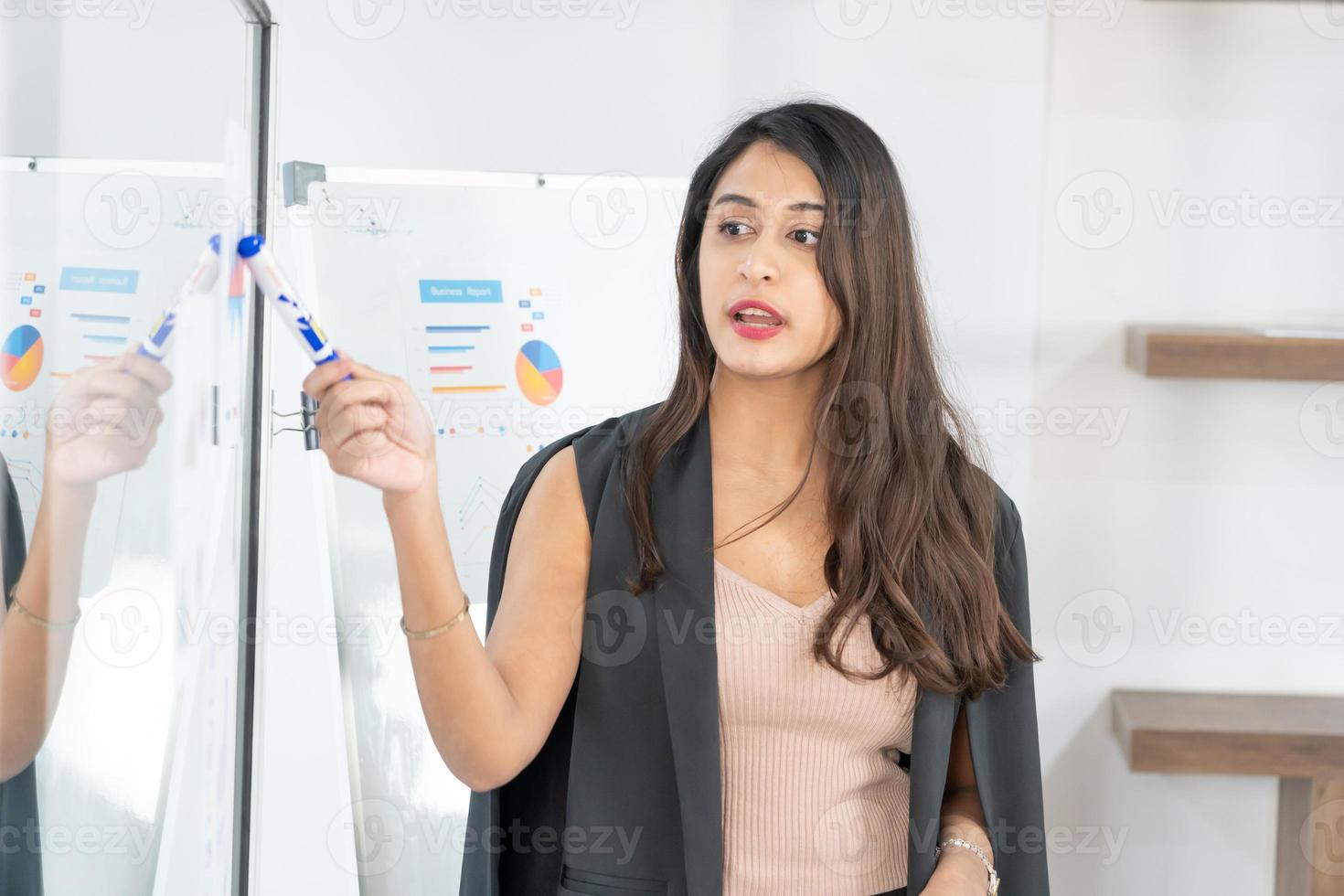 linda empresária dá relatório, apresentação para seus colegas de trabalho na sala de conferências, ela mostra gráficos. profissional de negócios feminino de sucesso. foto