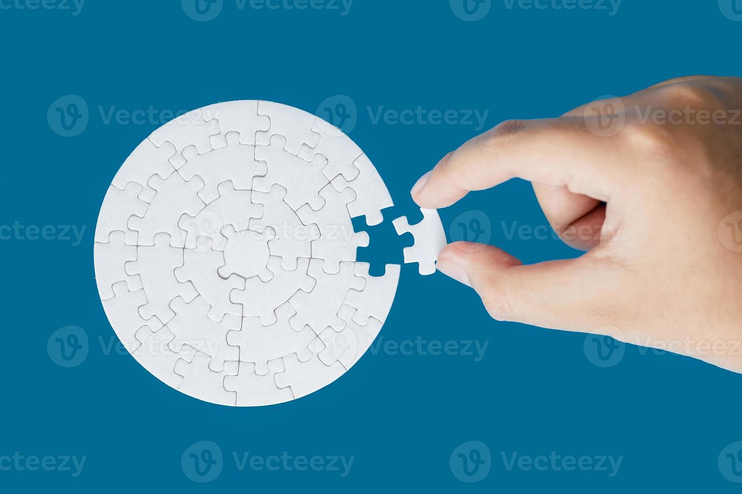 feche a mão segurando e jogando o jogo de quebra-cabeça incompleto. parte branca de peças de quebra-cabeça sobre fundo azul. conceitos de resolução de problemas, negócios, trabalho em equipe, foto de textura com espaço de cópia para texto