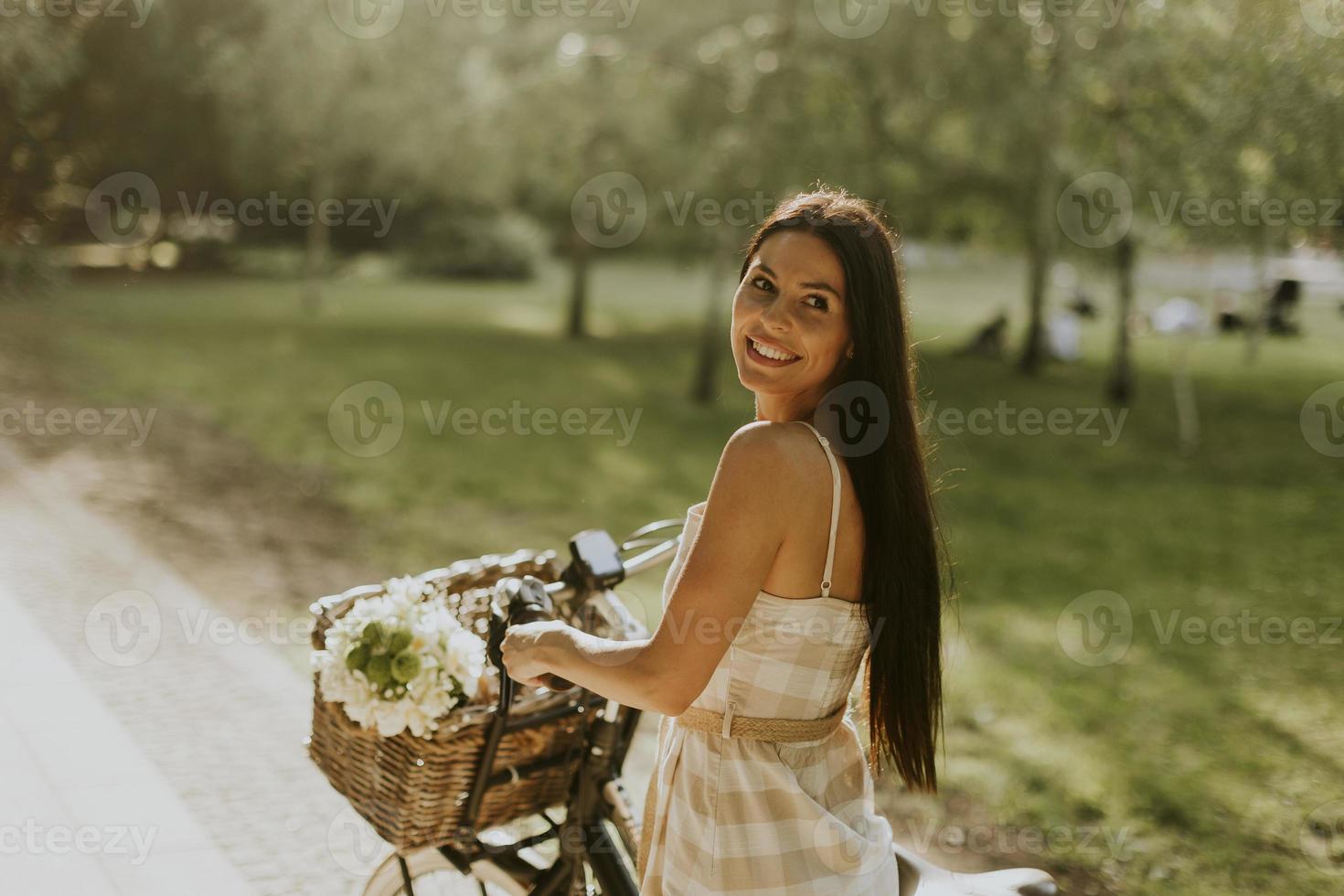 jovem mulher com flores na cesta de bicicleta elétrica foto