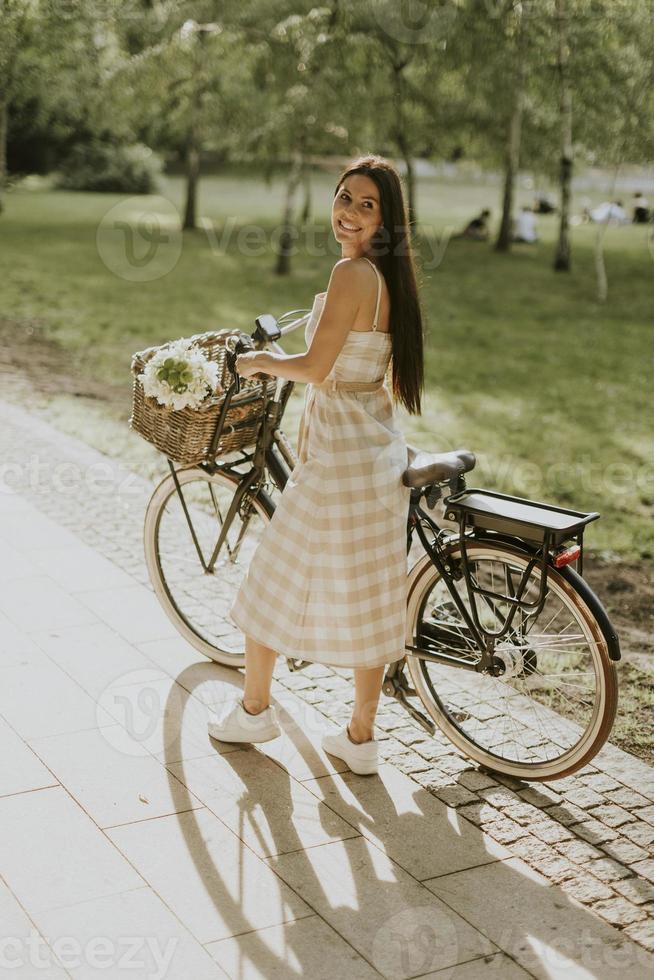 jovem mulher com flores na cesta de bicicleta elétrica foto