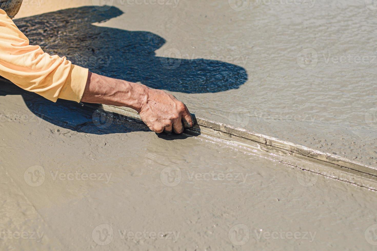 trabalhador ele está usando a espátula e nivelando o concreto no chão do edifício despejando a laje de concreto foto