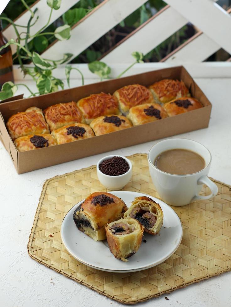 bola de chocolate ao leite lanche pão apreciado com um copo de café com leite foto