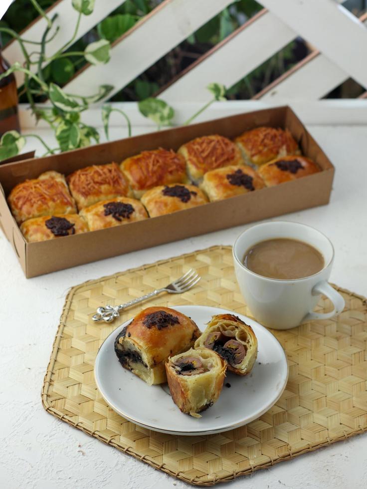 bola de chocolate ao leite lanche pão apreciado com um copo de café com leite foto